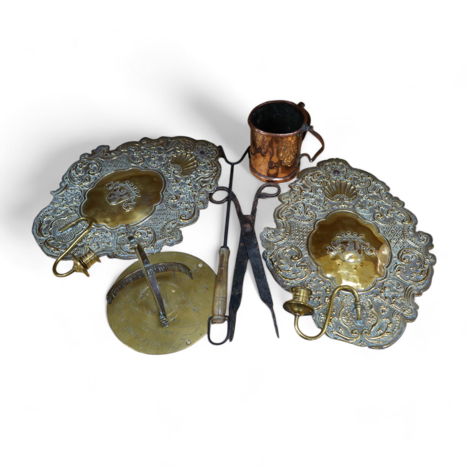 A pair of brass repousse wall sconces, a copper two handle mug, a small brass sun dial, a pair of tongs and a roasting trivet. Condition - poor to fair